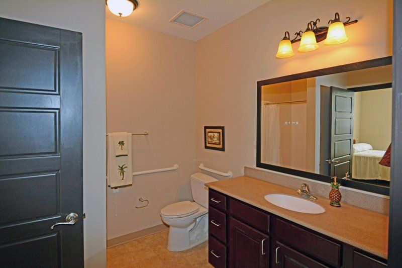 A modern bathroom featuring a sink, toilet, and mirror with warm lighting.