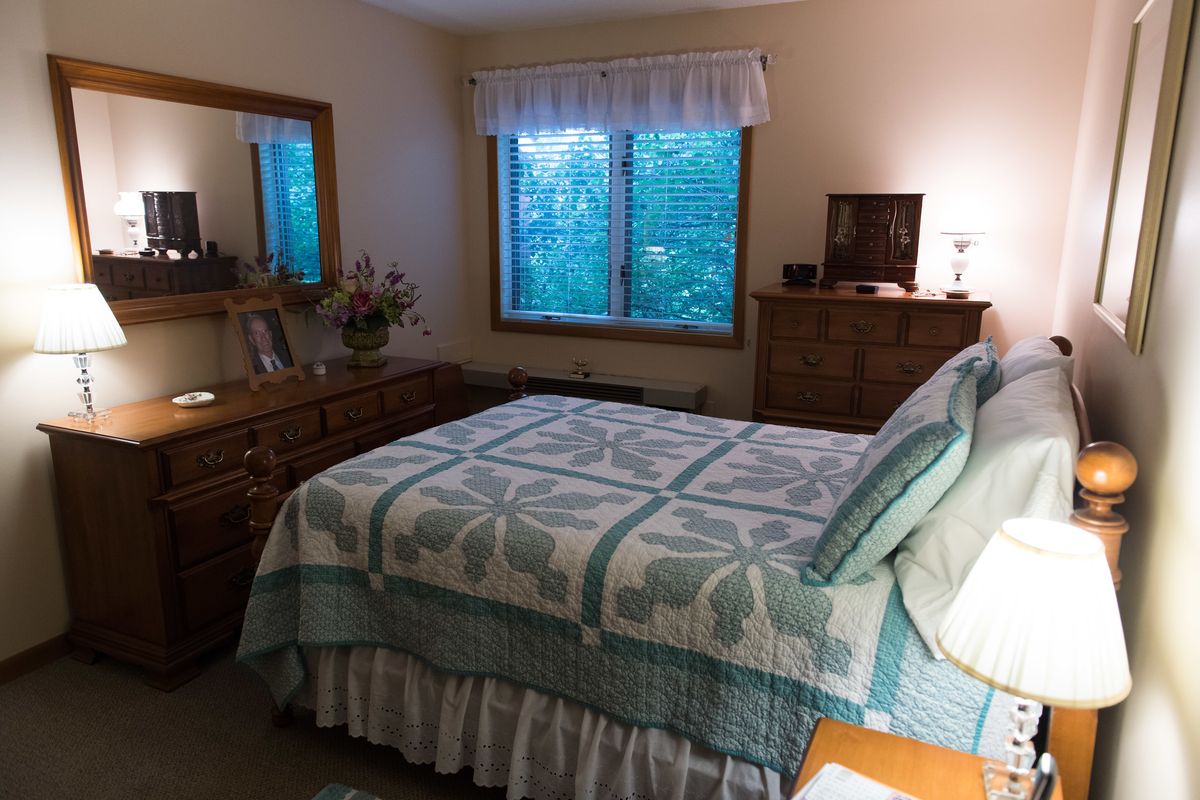 A cozy bedroom with a neatly made bed, wooden furniture, and a window view.