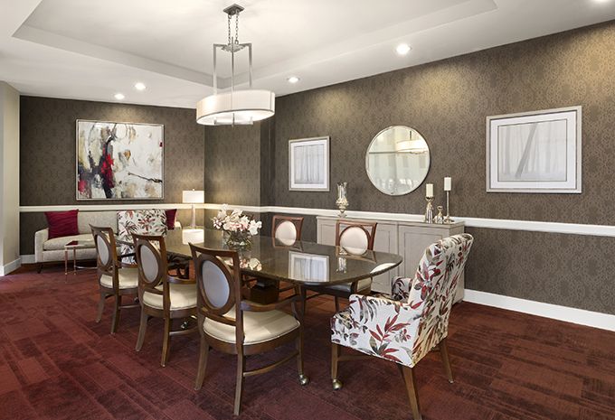 Elegant dining room with a modern chandelier, a large table surrounded by stylish chairs, and decorative wall elements.