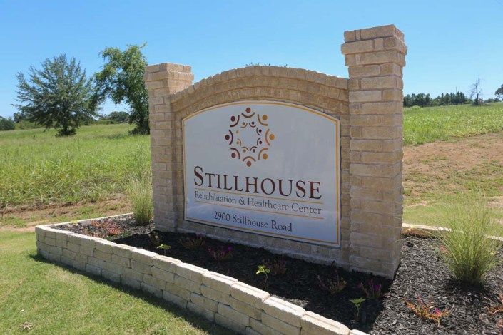 A stone entrance sign for Stillhouse on a grassy landscape.