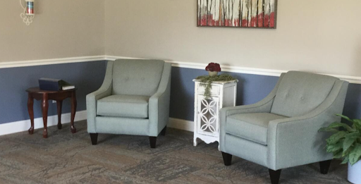 A cozy seating area featuring two light blue chairs and a white side table adorned with decorative elements.
