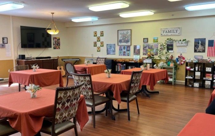 An indoor dining room with several tables and chairs, featuring decorative elements on the walls.