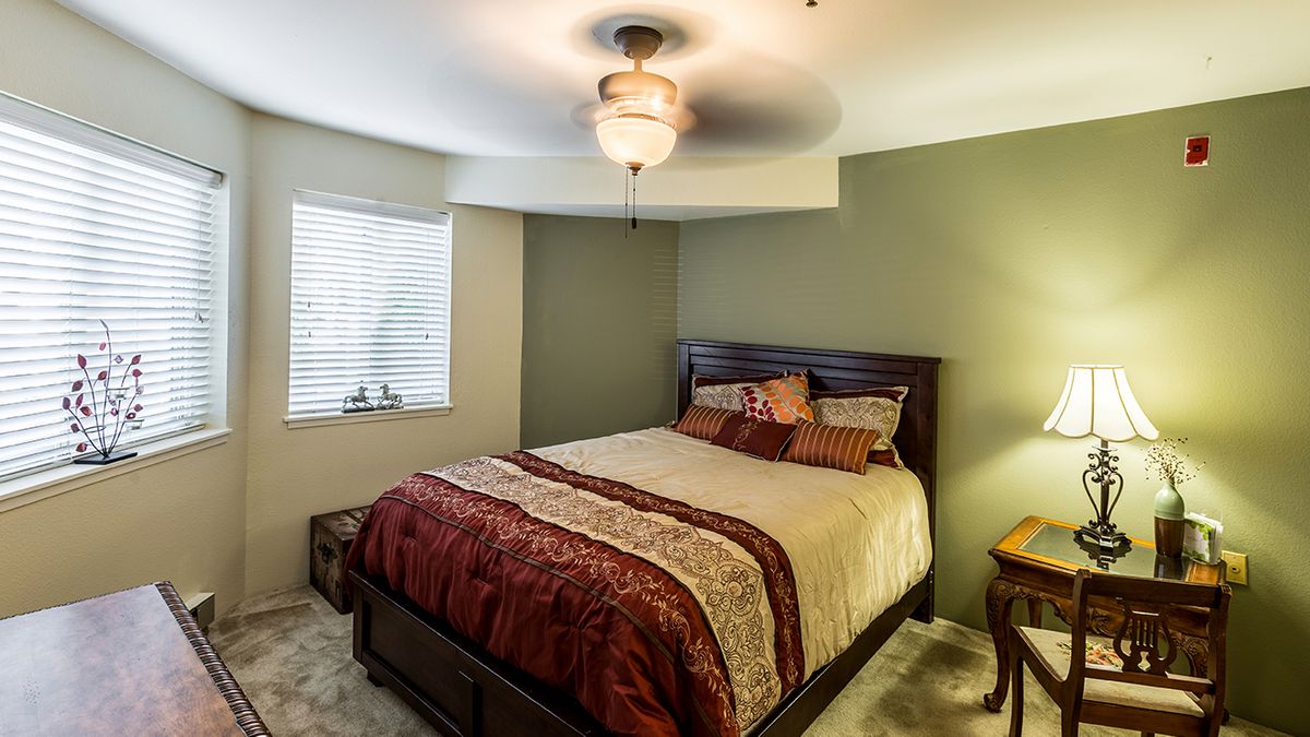 A cozy bedroom with a comfortable bed, ceiling fan, and soft lighting.