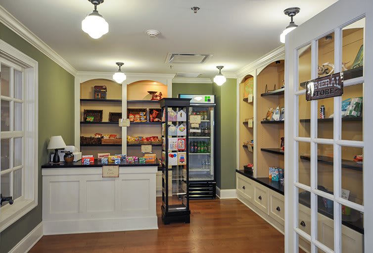 A small shop interior with wooden floors, shelves stocked with products, and a counter.