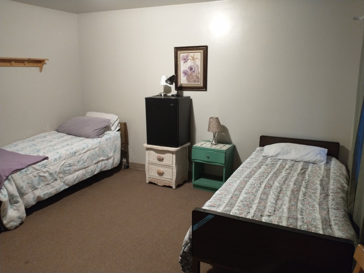 A simple bedroom with two twin beds and minimalist decor.