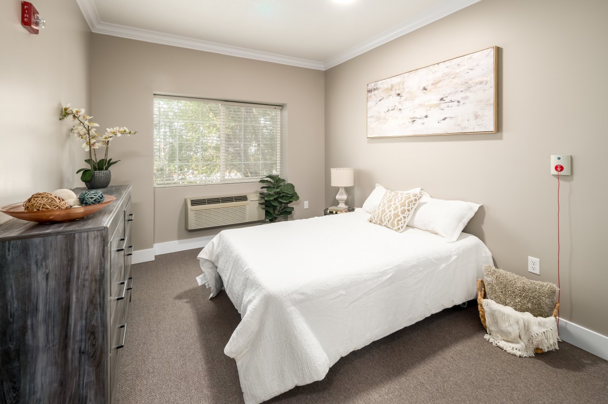 A modern bedroom with white bedding and minimalist decor.