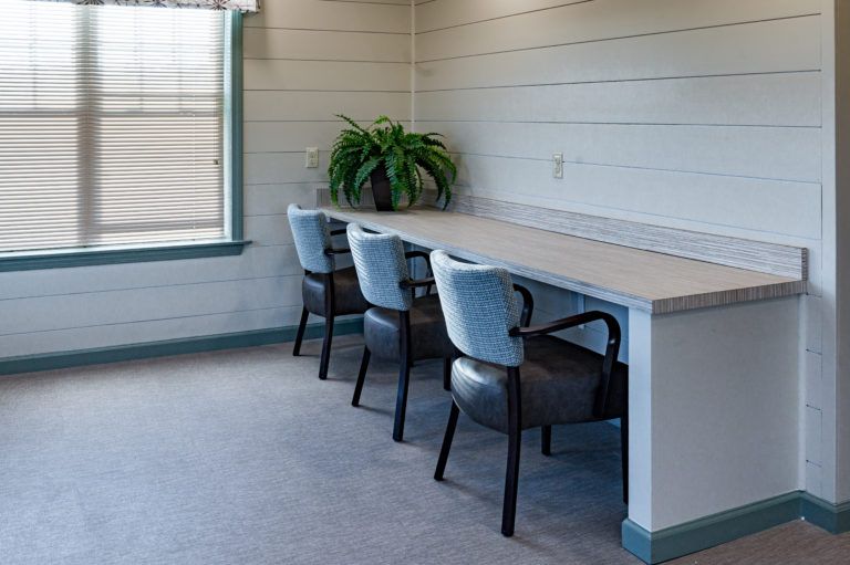 A clean and organized office workspace with chairs, a desk, and a plant.