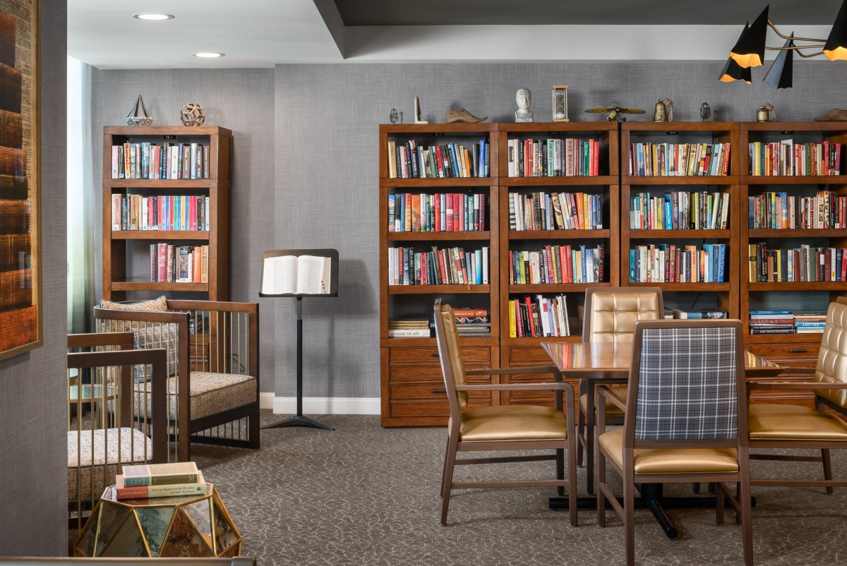 A cozy library with bookshelves, chairs, and tables arranged for reading and study.