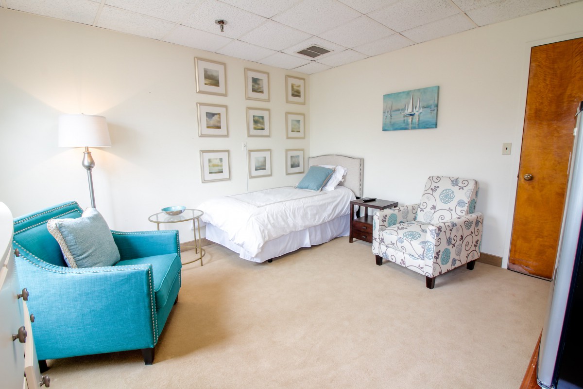 A cozy bedroom with a bed, chairs, and decorative elements.