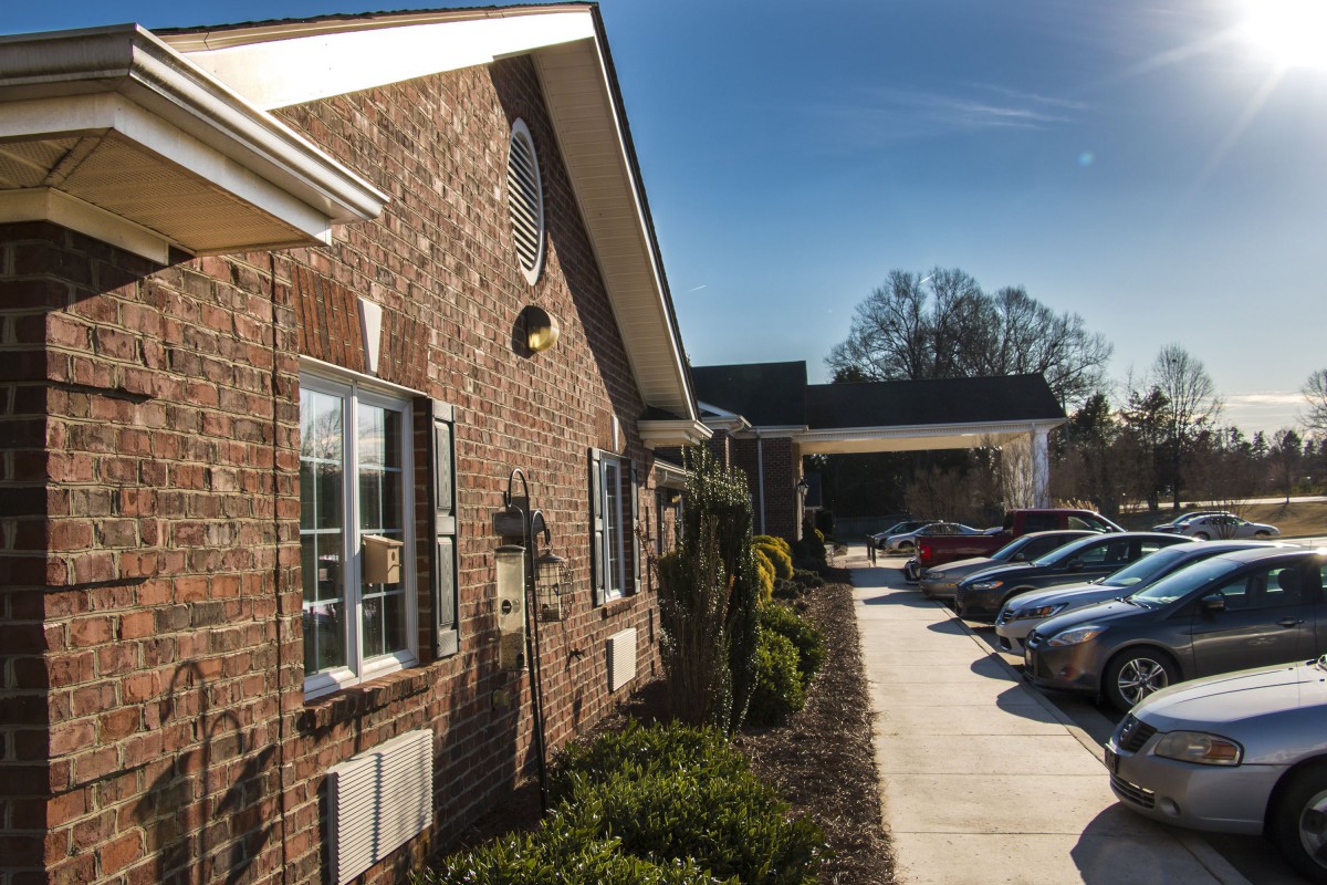 A brick building with a parking lot full of cars on a sunny day.