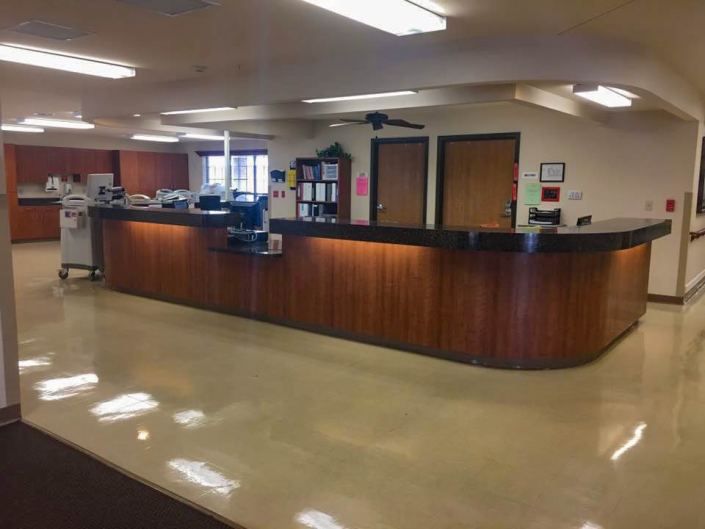 A reception desk in an office with a clean, polished floor and overhead lighting.