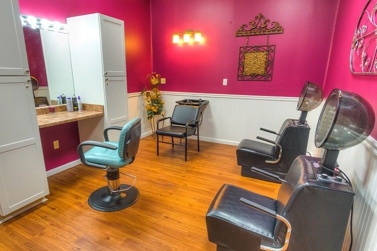 An inviting beauty salon with vibrant pink walls, stylish chairs, and a well-lit mirror.