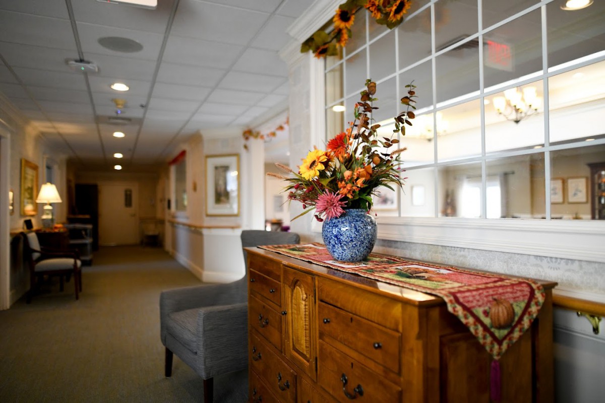 A warmly decorated hallway featuring a wooden dresser with a vase of colorful flowers.