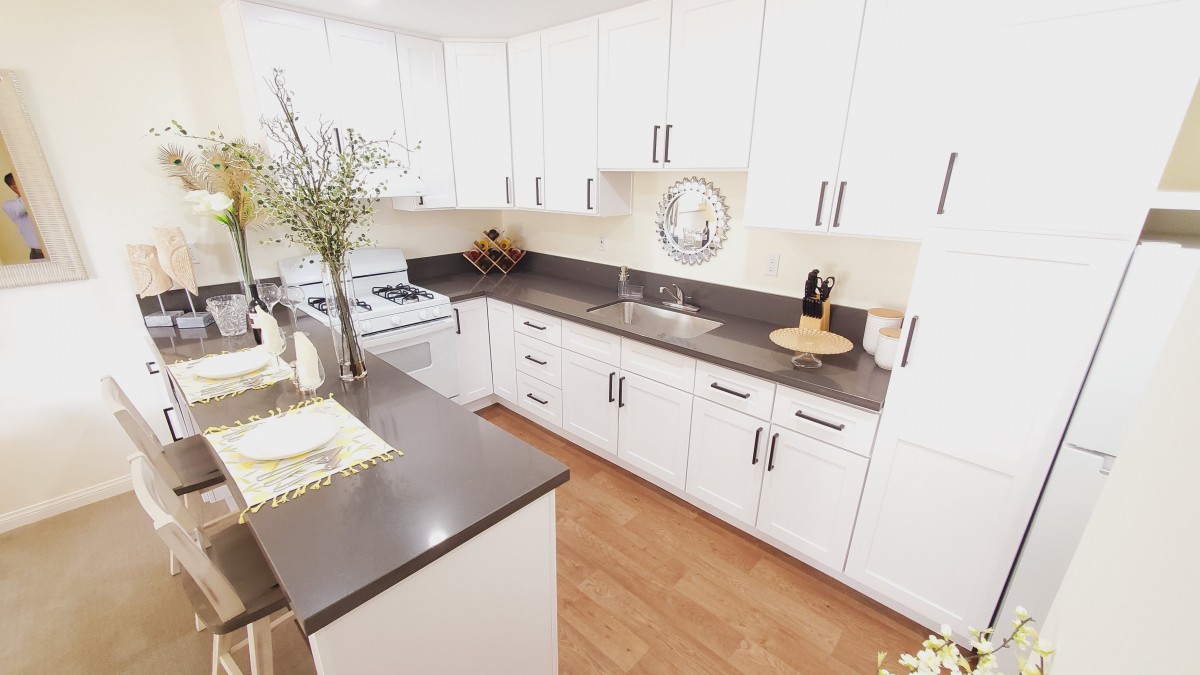 A modern kitchen with white cabinets and a sleek gray countertop.