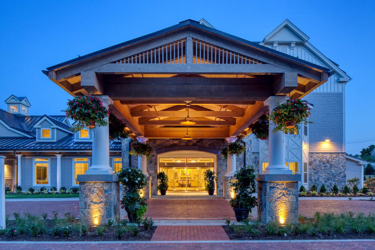 A beautifully lit entrance with columns at a building during the evening.