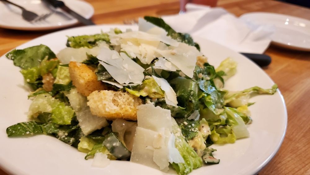 A fresh Caesar salad topped with crispy croutons and shaved Parmesan cheese.