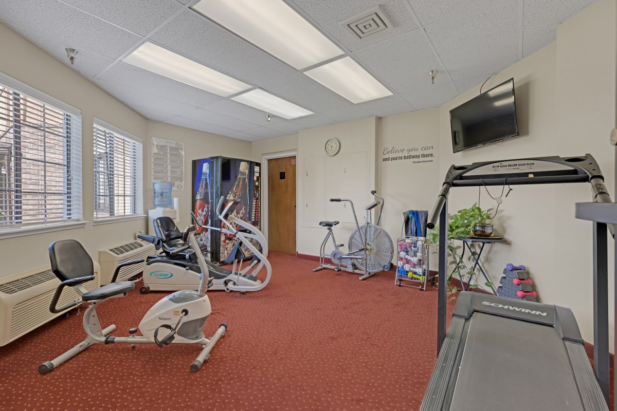 A small indoor gym with various exercise equipment including treadmills and stationary bikes.
