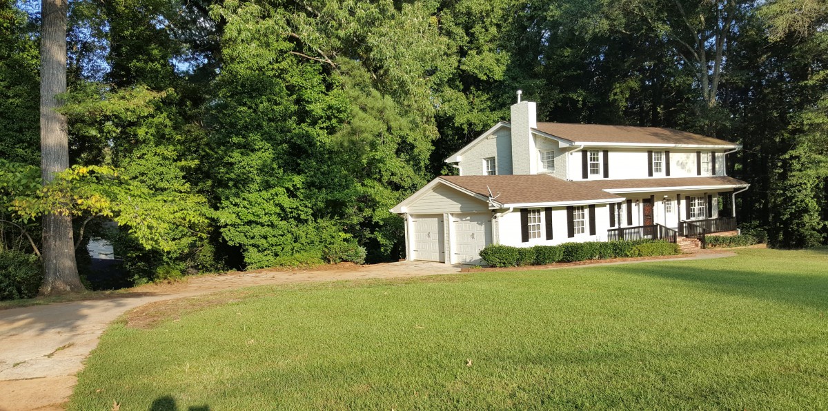 A suburban house surrounded by trees and a well-maintained lawn.