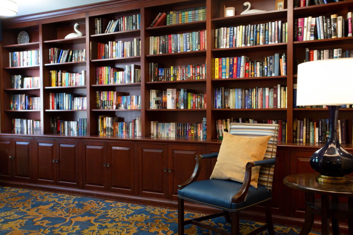 A cozy library corner with a well-stocked bookshelf and a comfortable chair.