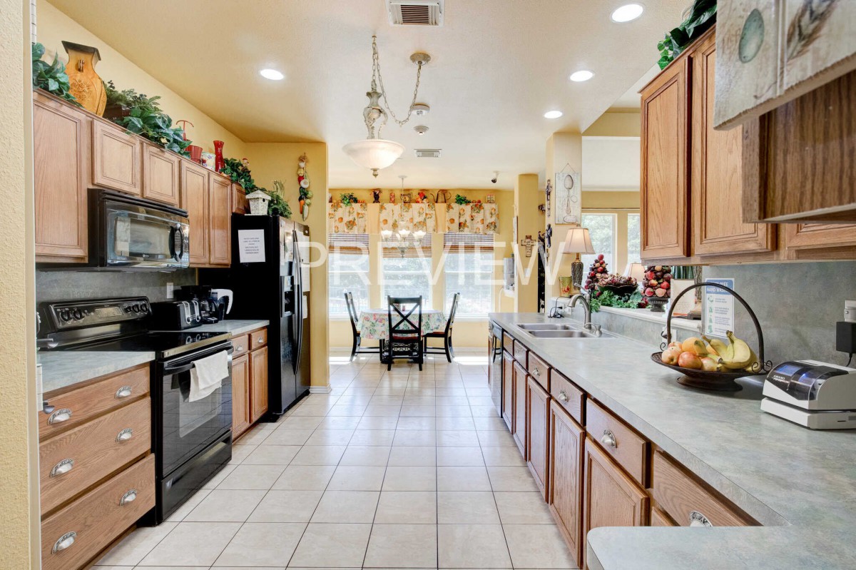 A spacious kitchen with wooden cabinets, modern appliances, and a sunlit dining area.
