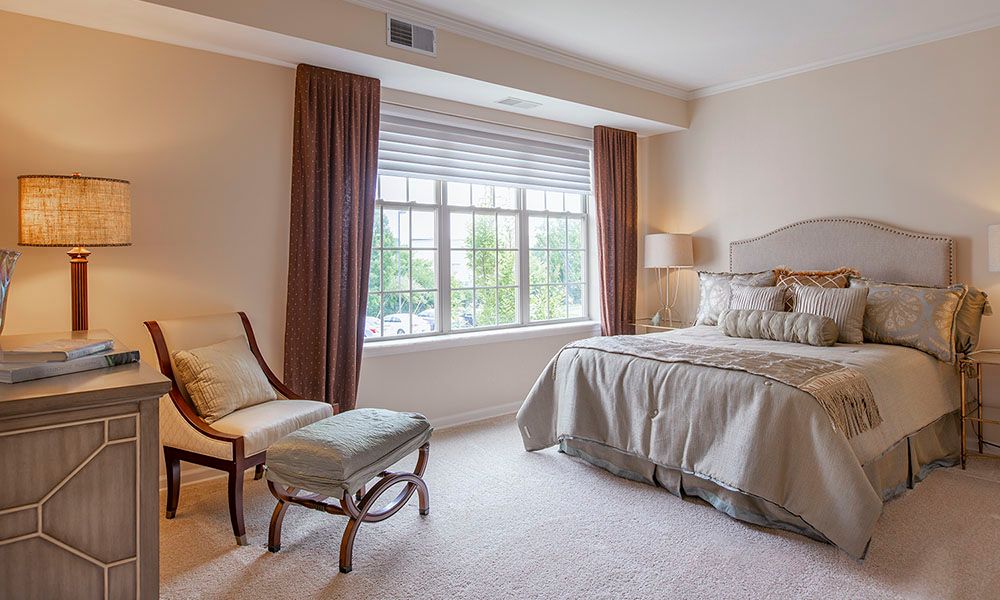 A cozy bedroom with a large window, elegant curtains, and comfortable furniture.