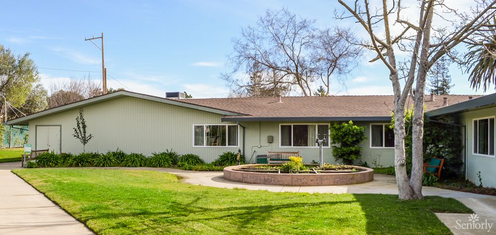 A suburban house with a well-maintained lawn and surrounding trees.