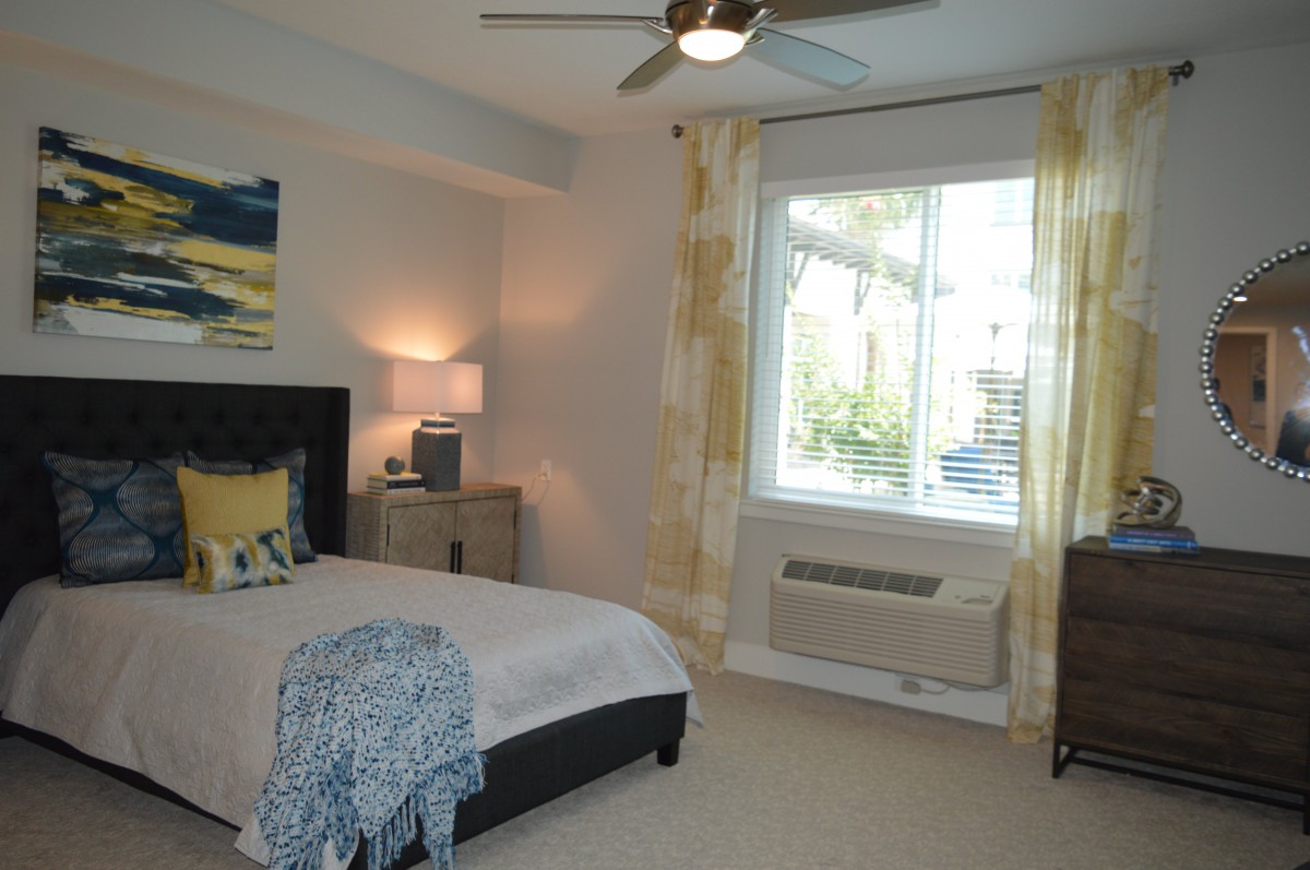 A modern bedroom with a large window, stylish bed, and cozy decor.