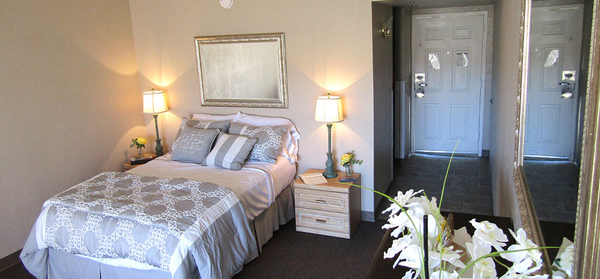 A cozy bedroom with a neatly made bed, decorative pillows, and bedside lamps.