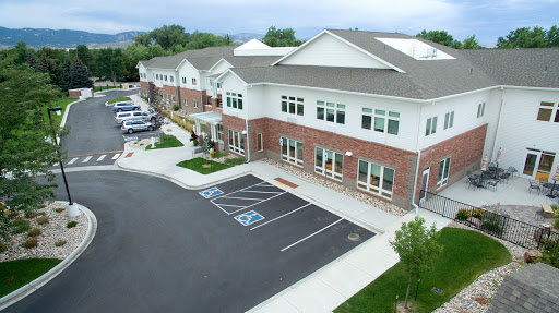 A modern residential building with accessible parking spots, surrounded by green landscaping under a cloudy sky.