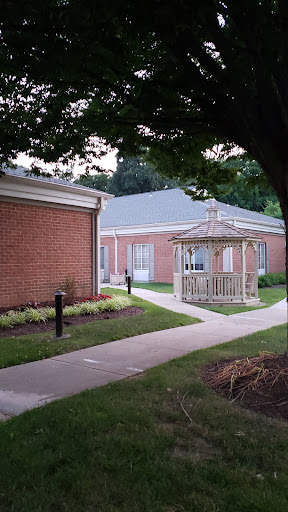 A serene view of a brick building with a charming gazebo surrounded by well-maintained landscaping.