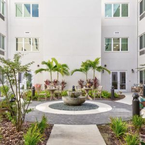 A serene courtyard featuring a central fountain and lush greenery.