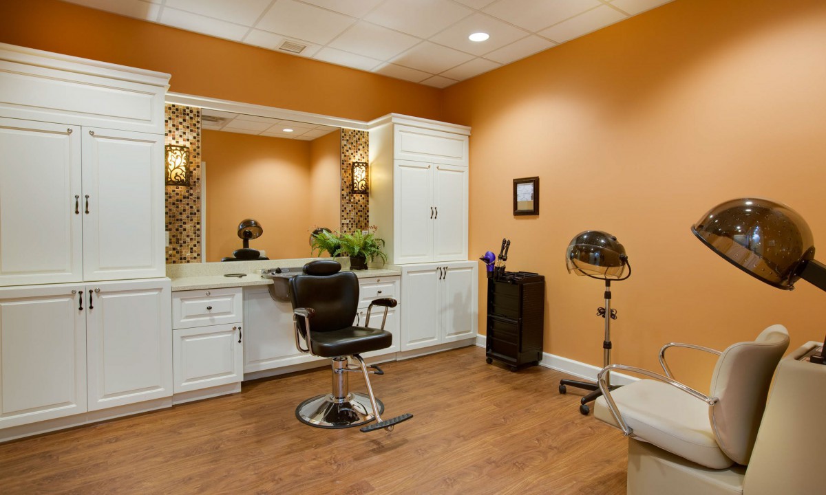 A modern salon interior with a hairdresser chair, mirror, and orange walls.
