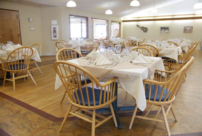 A neatly arranged dining area with elegant table settings and wooden chairs.