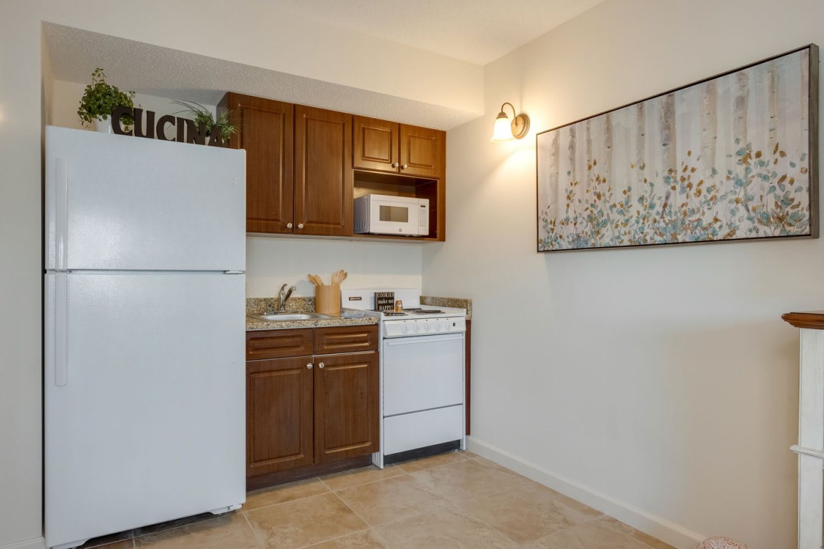 A small apartment kitchen featuring a refrigerator, microwave, and stove with wooden cabinets and modern decor.