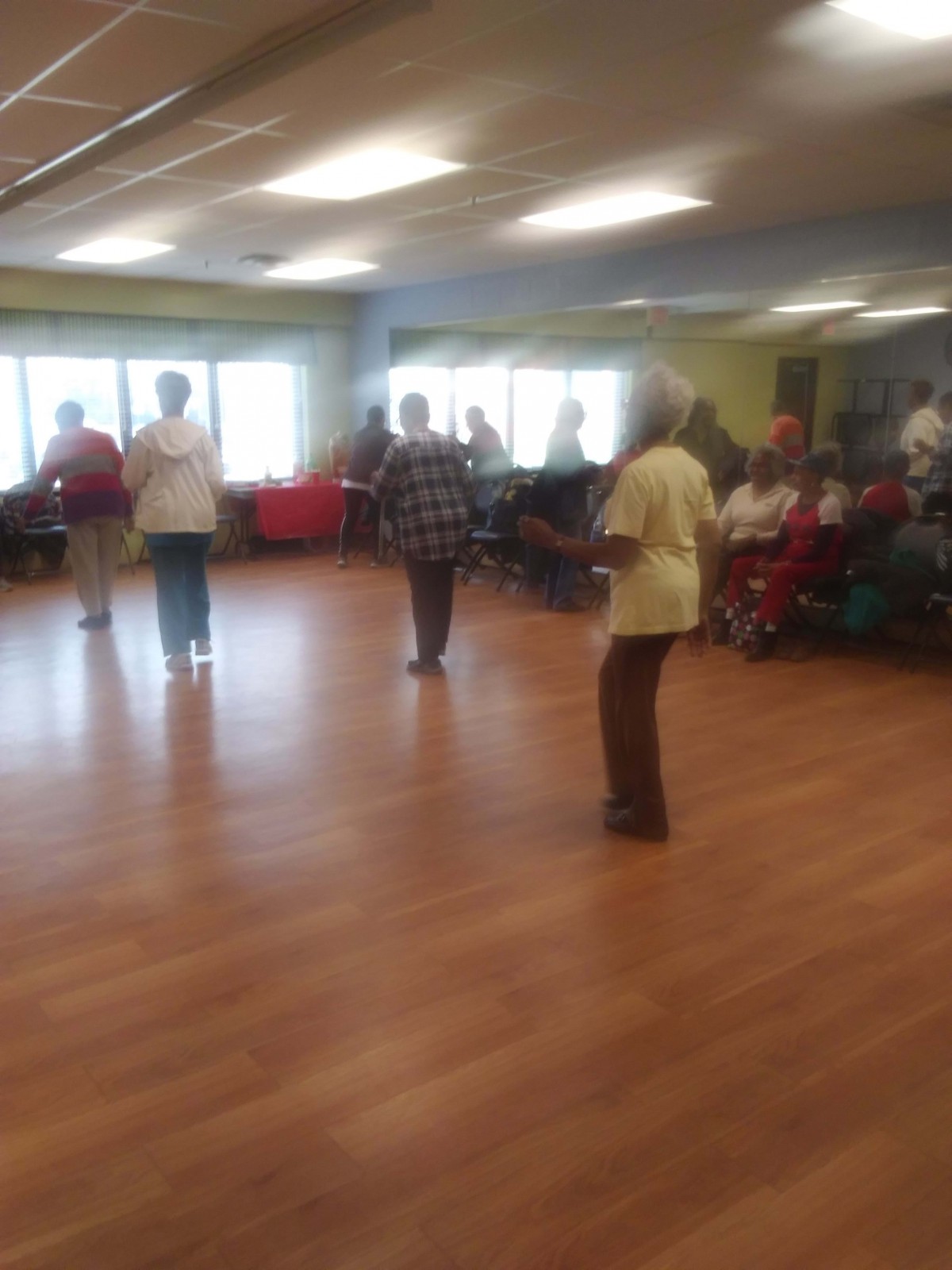 A group of seniors participating in a dance session indoors.