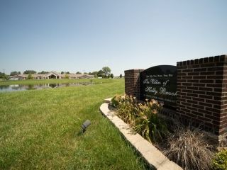 A sunny suburban landscape featuring a grassy field and a brick sign.
