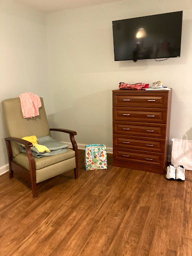 A cozy room featuring a comfortable chair, a dresser, and a television mounted on the wall.