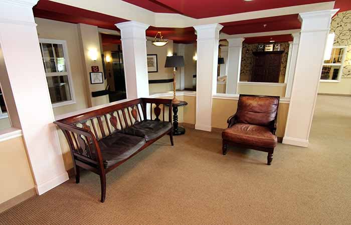 A cozy lobby with a wooden bench and leather chair.