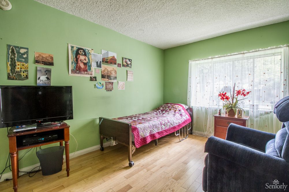 A cozy bedroom with green walls, a single bed, and a television.
