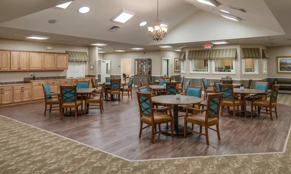 A cozy dining area with multiple tables and chairs, adorned with a chandelier and warm decor.