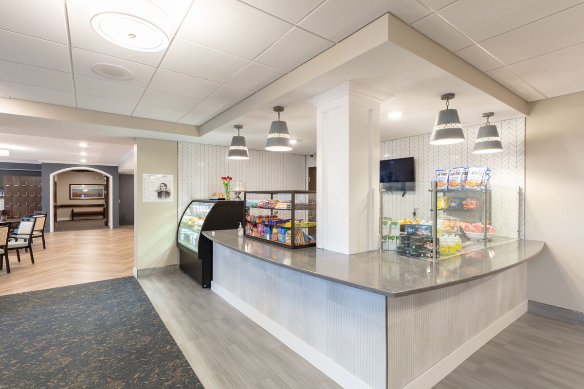 A modern and clean cafe interior with a central counter and display shelves.