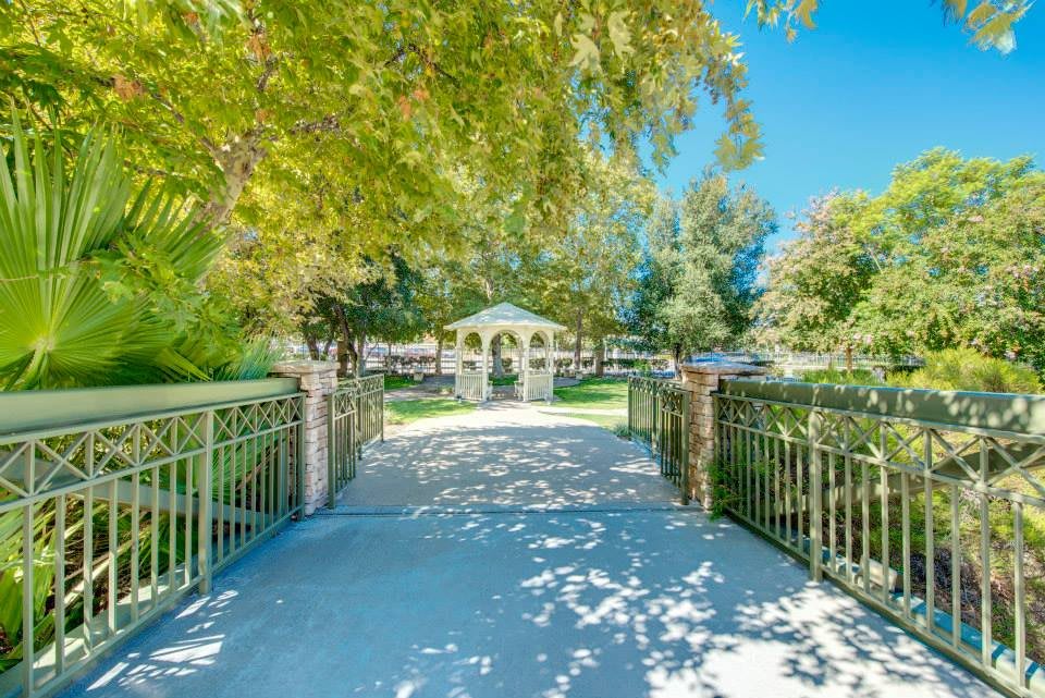 A scenic view of a house surrounded by lush greenery, with a sunlight-dappled pathway leading to its entrance.