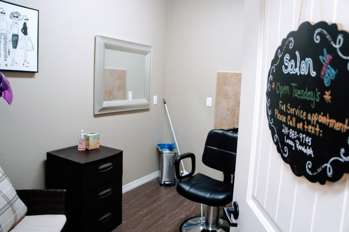 A small hair salon room featuring a chair, mirror, and storage drawers.