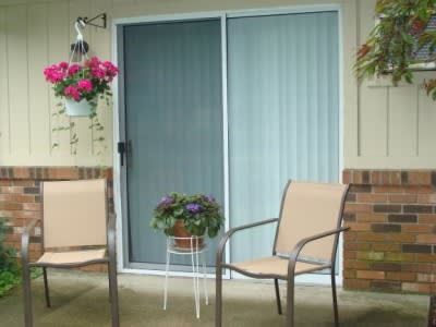 A cozy patio area with two chairs, potted plants, and a sliding glass door.