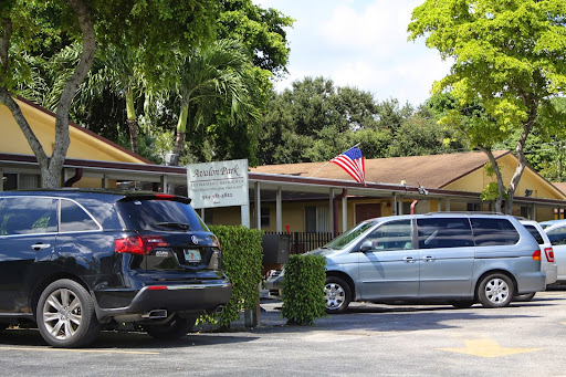 A view of a building with parked cars and an American flag in front.