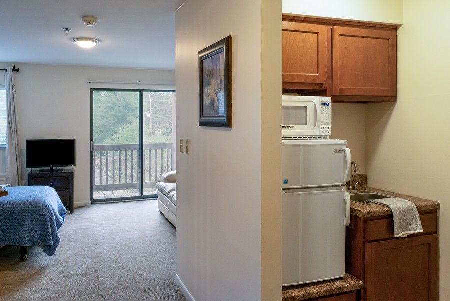 A small apartment with a kitchenette and a living area leading to a balcony.