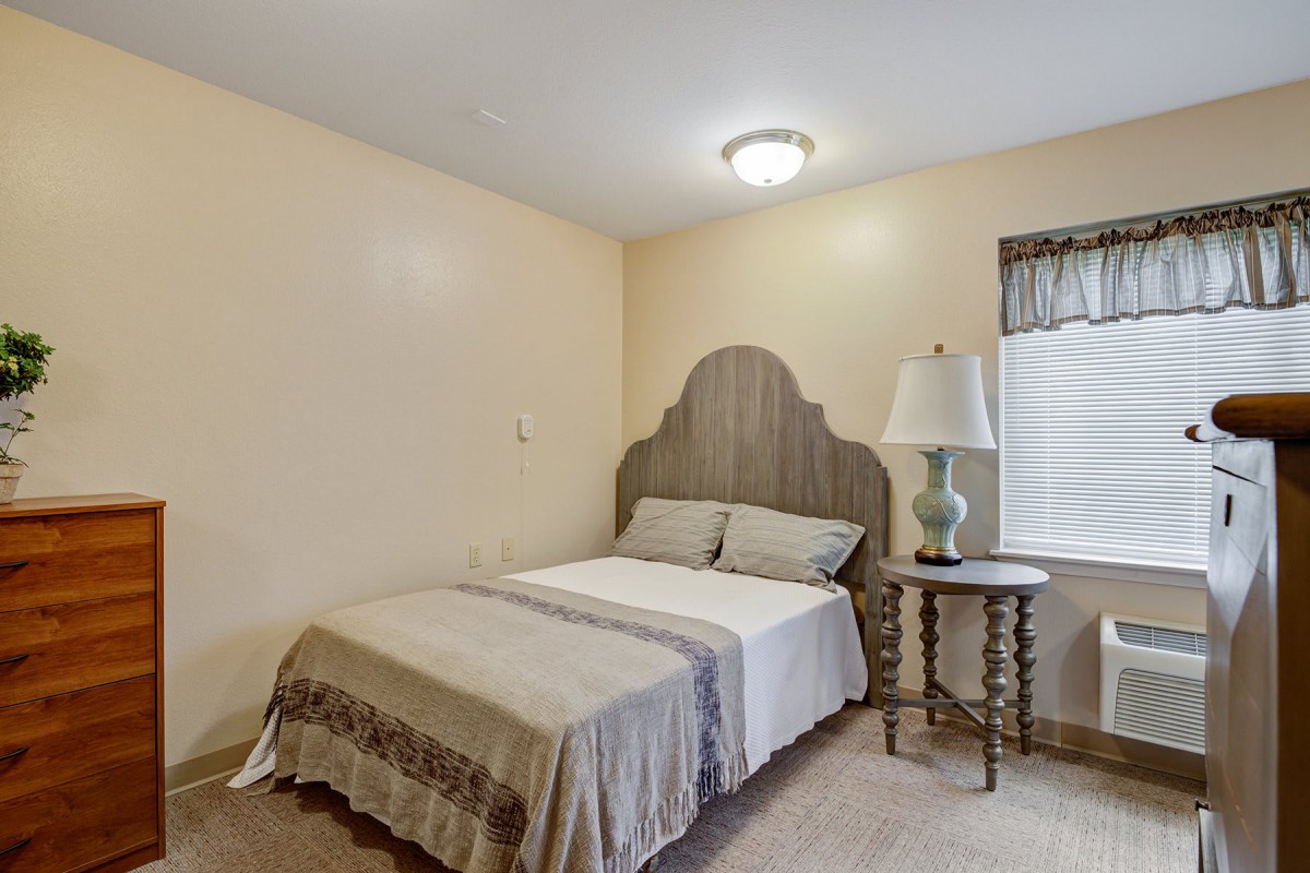 A cozy bedroom with a single bed and a side table next to a lamp.