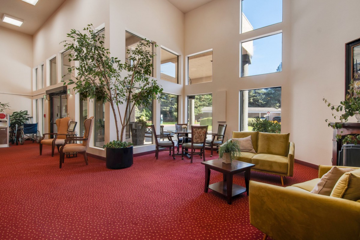 A spacious lobby with comfortable seating, large windows, and indoor plants.