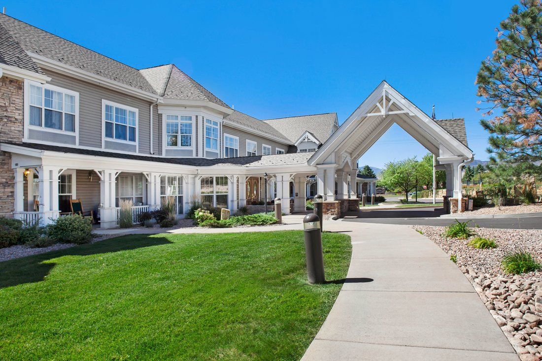 A front view of a residential building with a well-maintained lawn and clear blue skies.