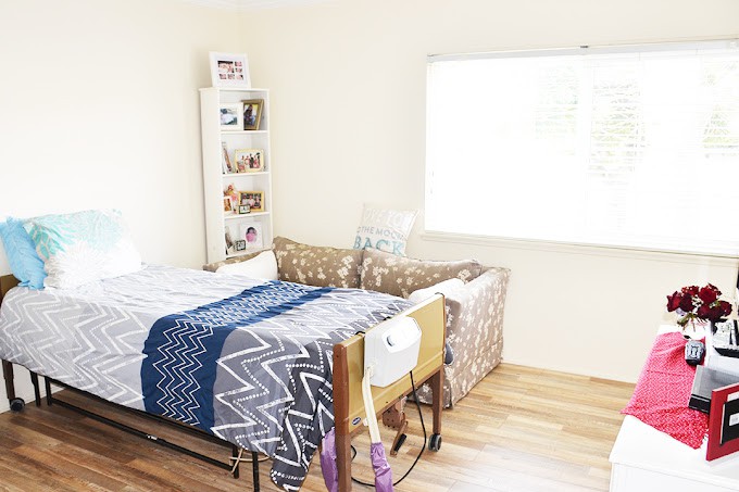 A minimalist bedroom with a neatly arranged bed and a bright window.